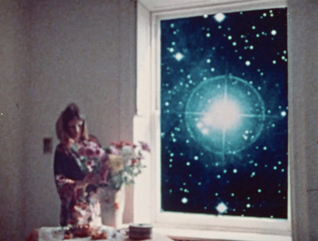 Still from Homage to Magritte by Anita Thacher, woman with flowers, universe through a window