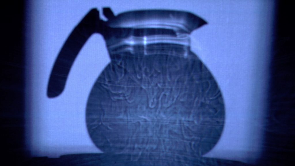 Image of a teakettle filled with other, its cast shadow on a wall