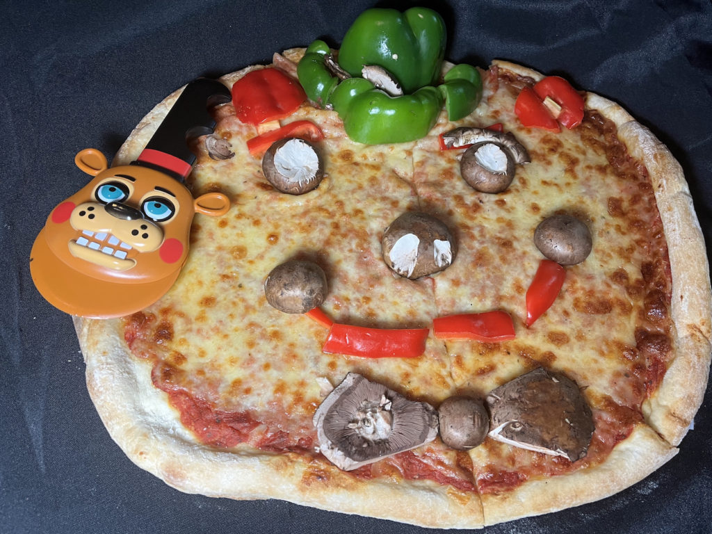 Pizza with face made with veggies and chocolate